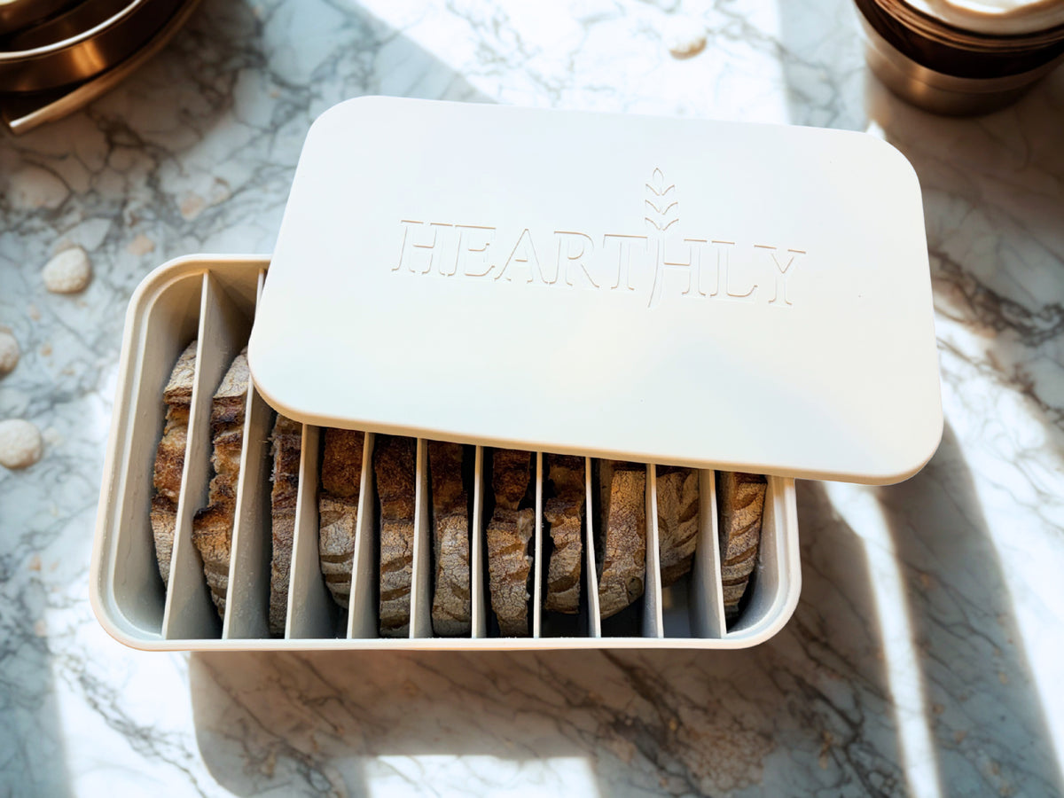 Hearthly silicone sourdough freezer storage container with individually separated bread slices on a marble countertop.